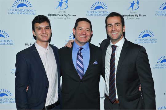 Three men in suits and ties pose together, smiling in front of a step and repeat backdrop featuring logos for Big Brothers Big Sisters of Los Angeles and The Foundation for Camp Bob Waldorf, a notable Jewish youth program.